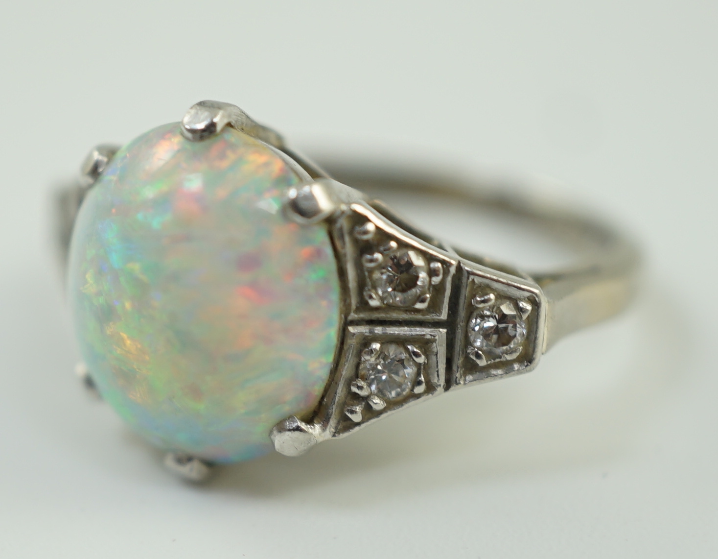 An 18ct white gold, platinum and single stone white opal set dress ring, with six stone diamond set shoulders